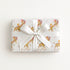 Vintage-style giraffe baby boy wrapping paper on a gift tied with a satin bow, baby boys riding giraffes in floral bonnets