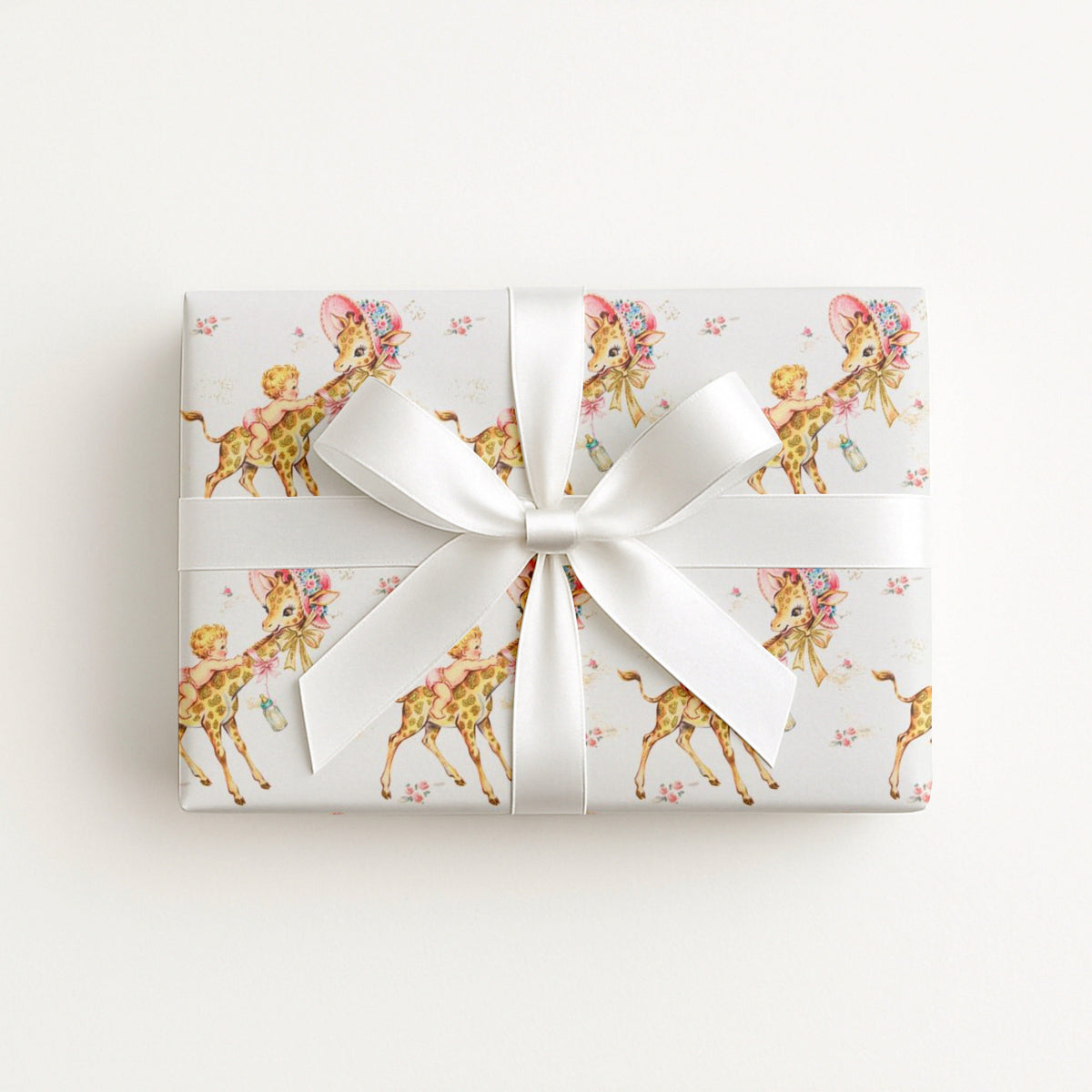 Vintage-style giraffe baby girl wrapping paper on a gift tied with a satin bow, baby girls riding giraffes in floral bonnets