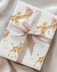 Gift wrapped in giraffe baby shower wrapping paper with a blush satin ribbon on soft cream fabric, baby boys riding giraffes in floral bonnets