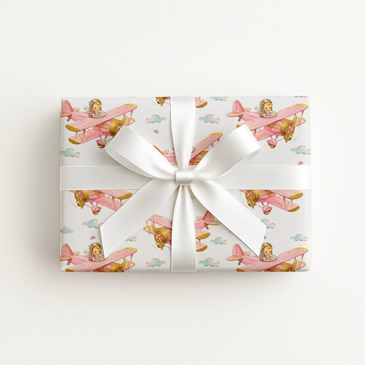 Girl airplane wrapping paper featuring two little pilots flying in a pastel pink vintage biplane.