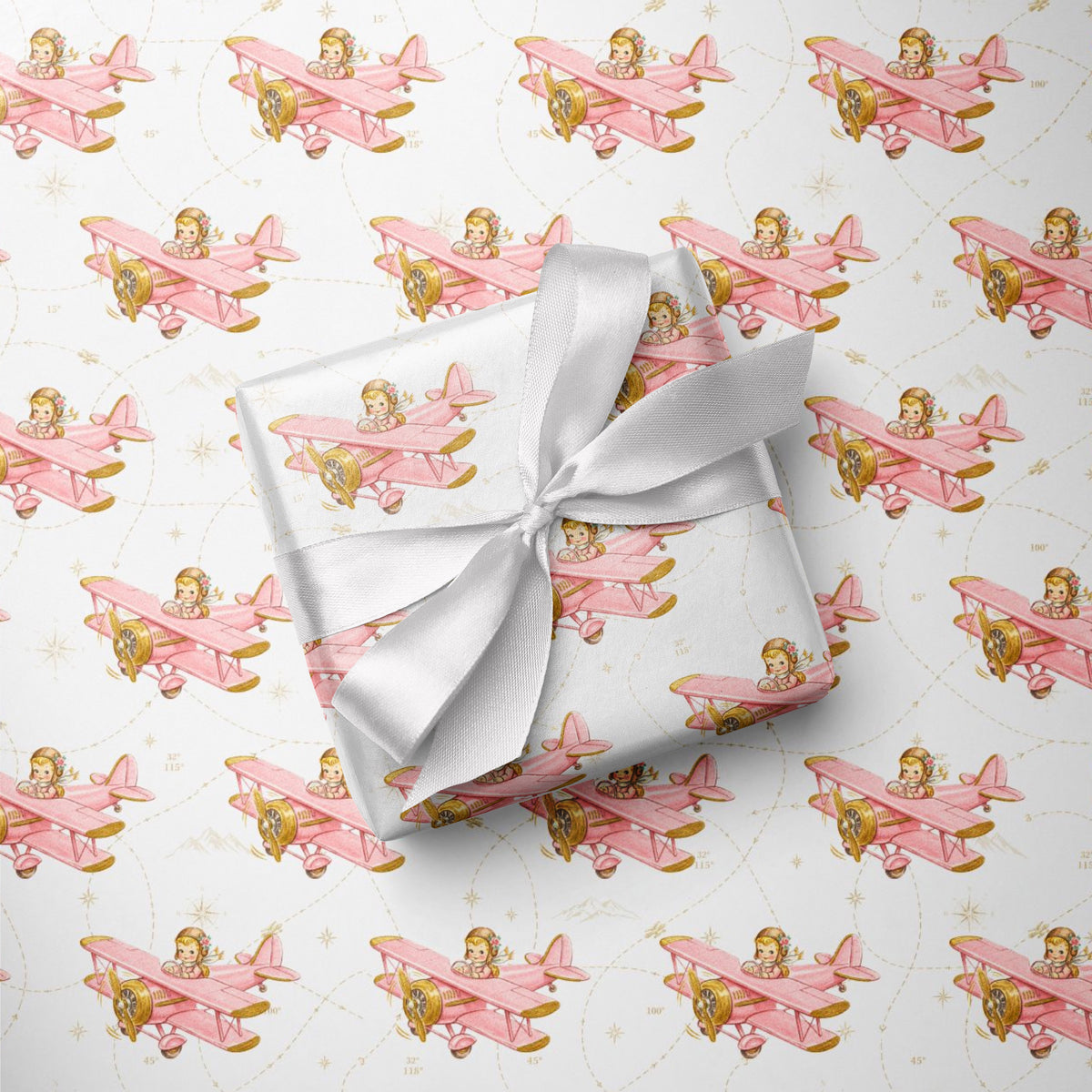 Wrapped gift tied with a white satin bow, displayed on matching wrapping paper featuring a little girl flying a pastel pink biplane over a delicate navigation map with gold accents on an ivory background.