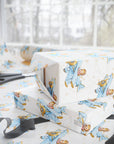 Gift boxes wrapped in paper featuring a little girl flying a powder blue biplane over a delicate aviation navigation map on an ivory background, displayed with an open roll of matching wrapping paper, dark ribbon, and scissors.