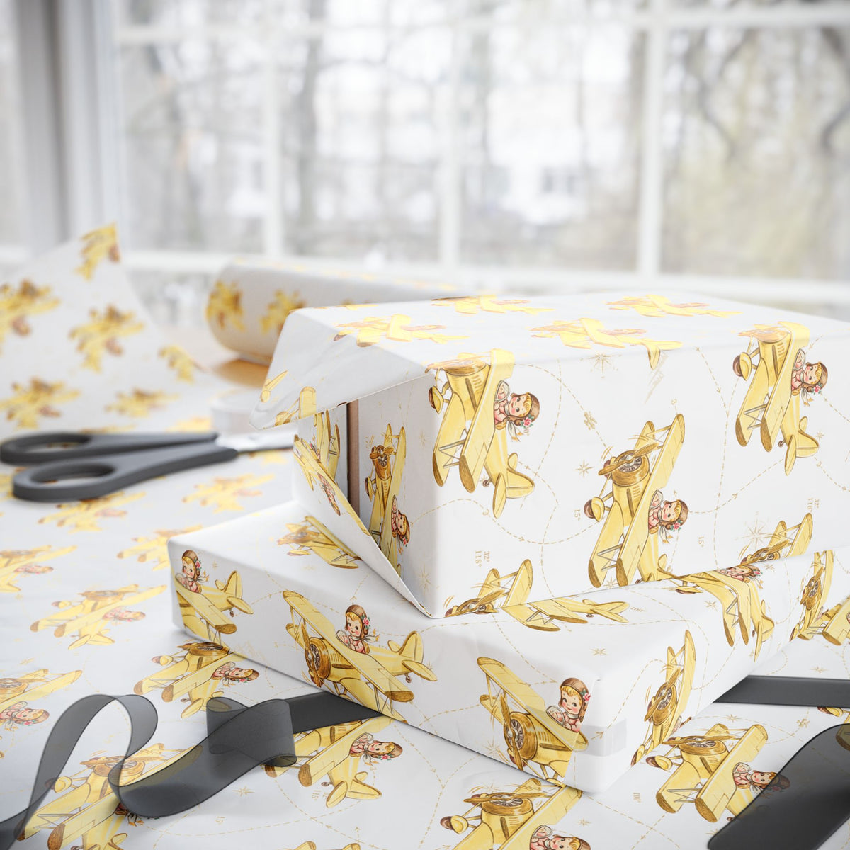 Gift boxes wrapped in paper featuring a little girl flying a pale yellow biplane over a delicate aviation navigation map on an ivory background, displayed with an open roll of matching wrapping paper, dark ribbon, and scissors.