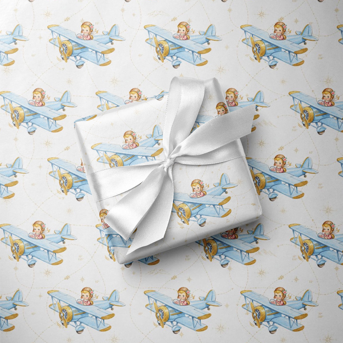 Wrapped gift tied with a white satin bow, displayed on matching wrapping paper featuring a little girl flying a powder blue biplane over a delicate navigation map with gold accents on an ivory background.