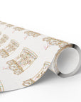 A roll of wrapping paper with a repeating pattern of ornate gold and pink carousel horses on a white background, shown partially unrolled on a clean white surface.
