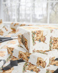 Gift wrap with Highland cow and baby design, scissors, and ribbons on a neutral background.