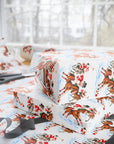 Stacked Christmas gifts wrapped in vintage-style polo match wrapping paper on a wrapping table with scissors and black ribbon