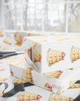 Stacked wedding gifts wrapped in ivory wedding cake wrapping paper on a wrapping table with scissors and sheer ribbon