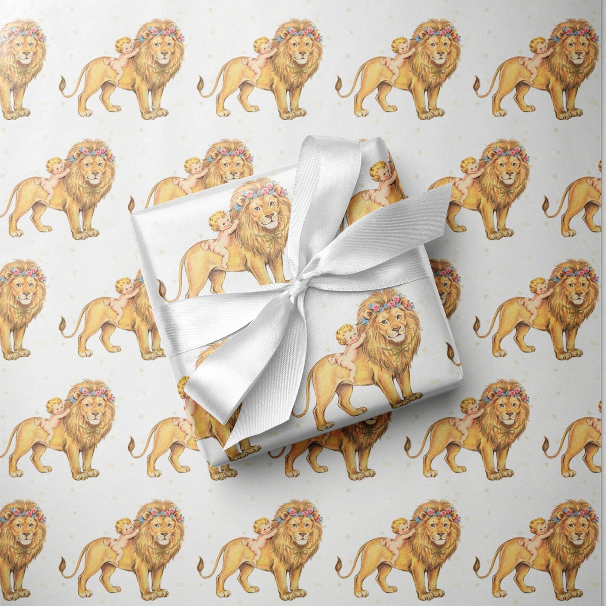 A gift wrapped in white satin ribbon with a bow, placed on top of matching wrapping paper printed with a repeating pattern of golden lions, flower crowns and sweet babies.