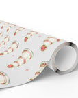 Roll of minimalist wedding cake wrapping paper with white tiered cakes, pink ribbons and rose clusters on a pale gray background