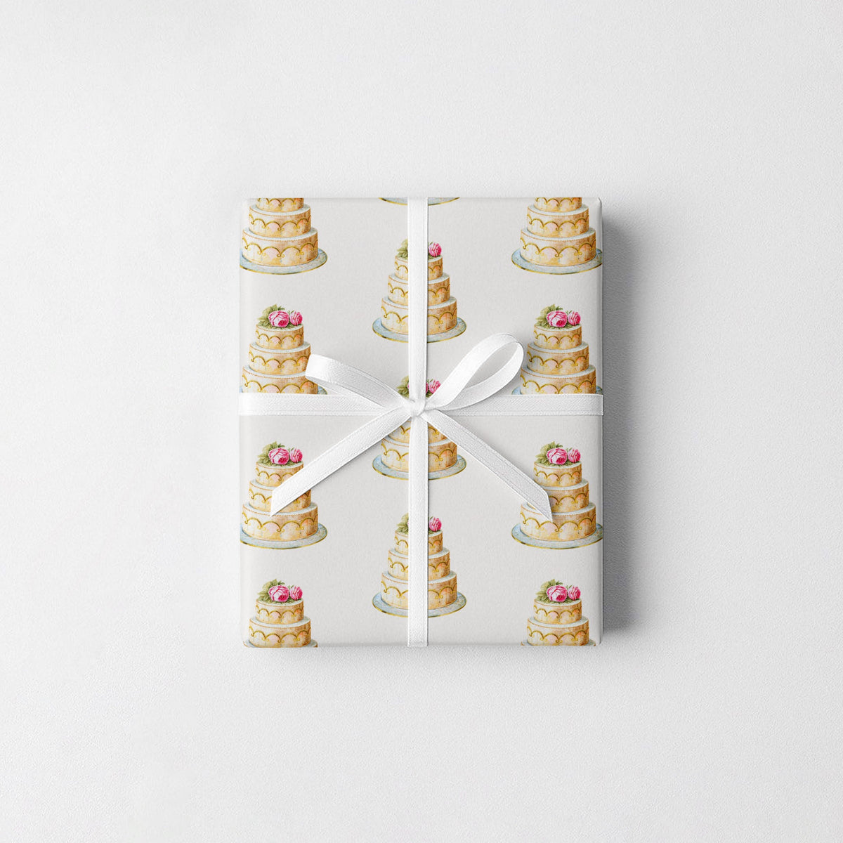 Gift wrapped in elegant ivory wedding cake wrapping paper with a slim white ribbon and small bow on a soft white surface
