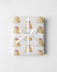 Gift wrapped in elegant ivory wedding cake wrapping paper with a slim white ribbon and small bow on a soft white surface
