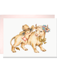 Vintage-style new baby girl card with a baby in a cowboy hat climbing a cream cow wearing a flower wreath and bow.