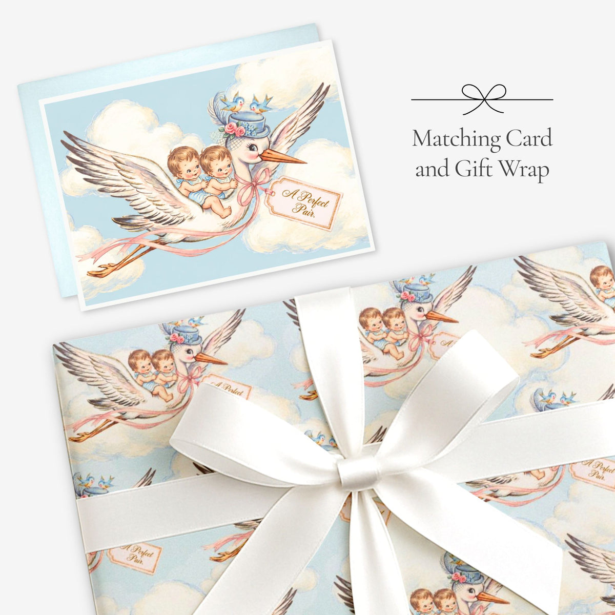 Twin boys stork card with matching twin boys stork gift wrap tied with a white satin bow, labeled Matching Card and Gift Wrap