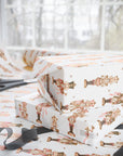 Stacked Christmas gifts wrapped in vintage-style pink nutcracker wrapping paper on a wrapping table with scissors and black ribbon