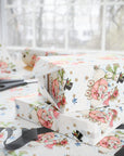 Stacked Christmas gifts wrapped in vintage-style snowman baby girl wrapping paper with a pink baby carriage on a wrapping table with scissors and black ribbon