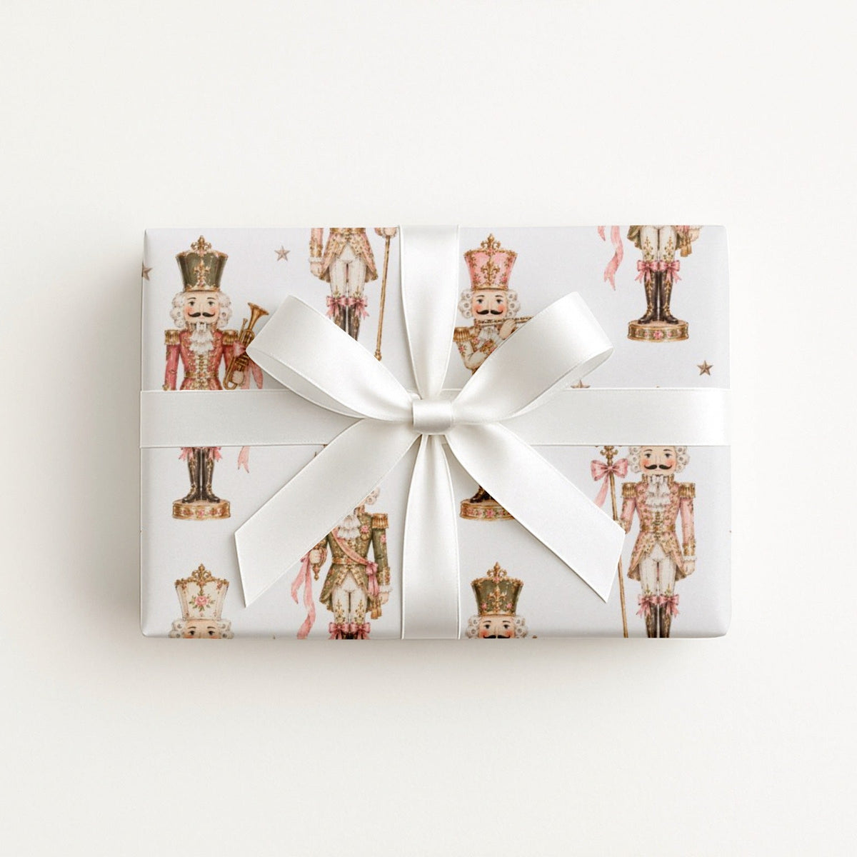 Gift wrapped in vintage-style pink and cream nutcracker soldier Christmas wrapping paper with a white satin bow, pink nutcracker gift wrap