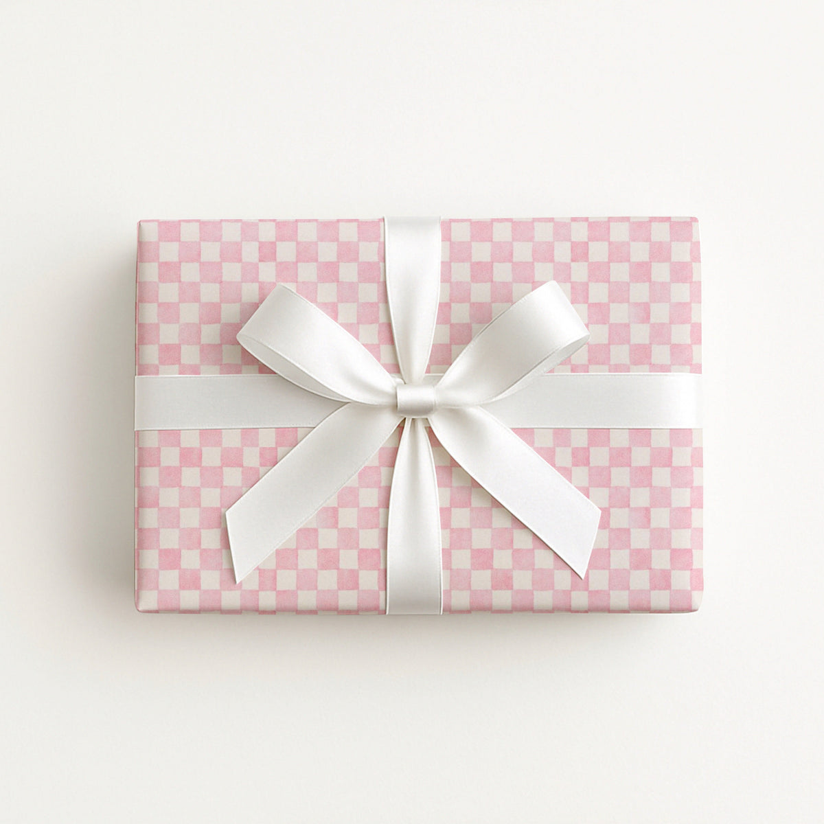 A rectangular gift box wrapped in pink and white checkered wrapping paper with a white satin ribbon tied in a bow, photographed from above on a clean white background.