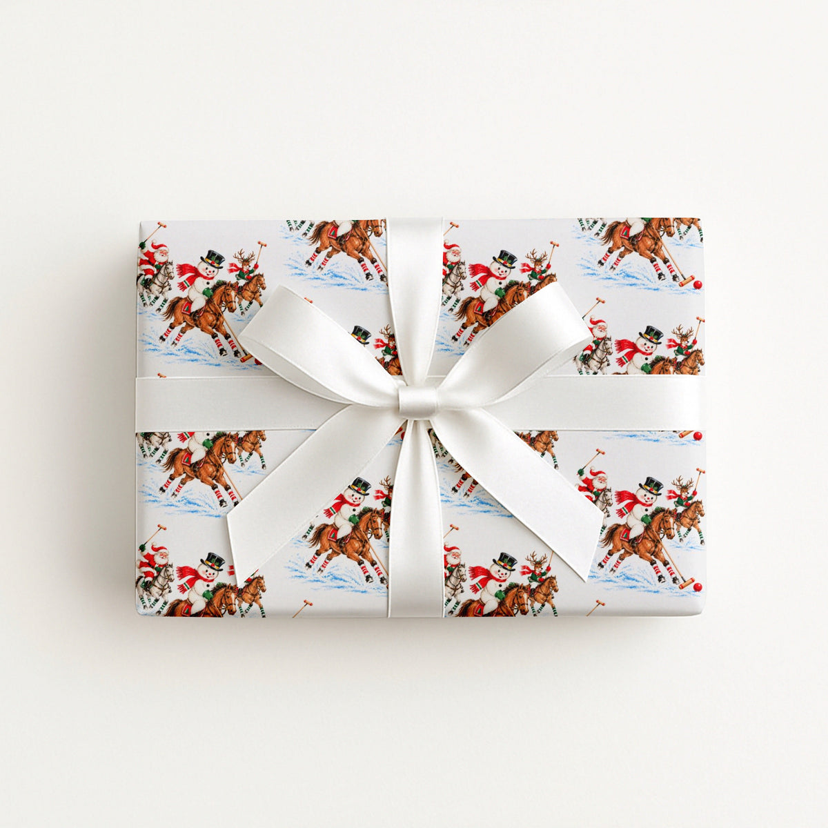 Flat lay of a gift wrapped in vintage-style polo match Christmas wrapping paper with a white satin bow