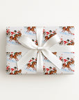 Flat lay of a gift wrapped in vintage-style polo match Christmas wrapping paper with a white satin bow