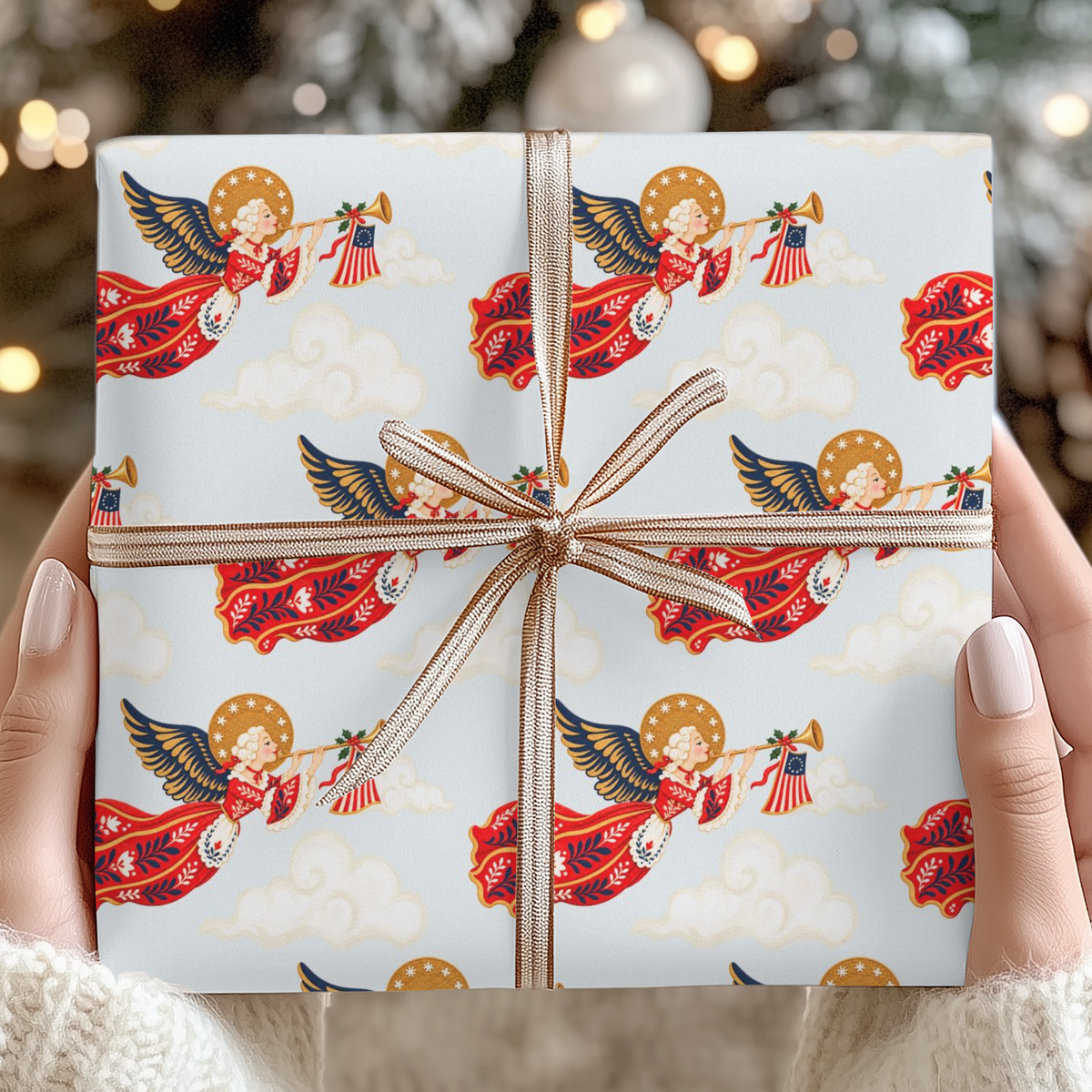 Hands holding a Christmas gift wrapped in vintage-style patriotic angel wrapping paper with a copper striped ribbon bow