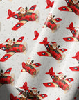 Ivory wrapping paper with a repeating pattern featuring Santa Claus flying vintage red airplanes with a star insignia.