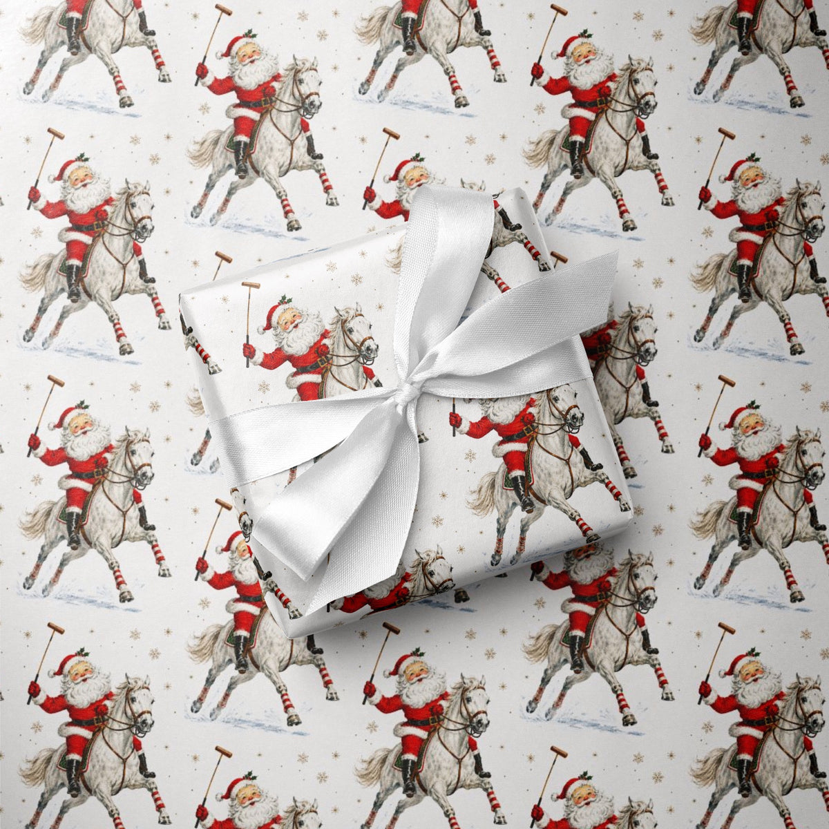 A wrapped gift box with a white satin ribbon sits on top of Christmas-themed wrapping paper featuring a repeating pattern of Santa Claus playing polo, horseback with a mallet in hand.