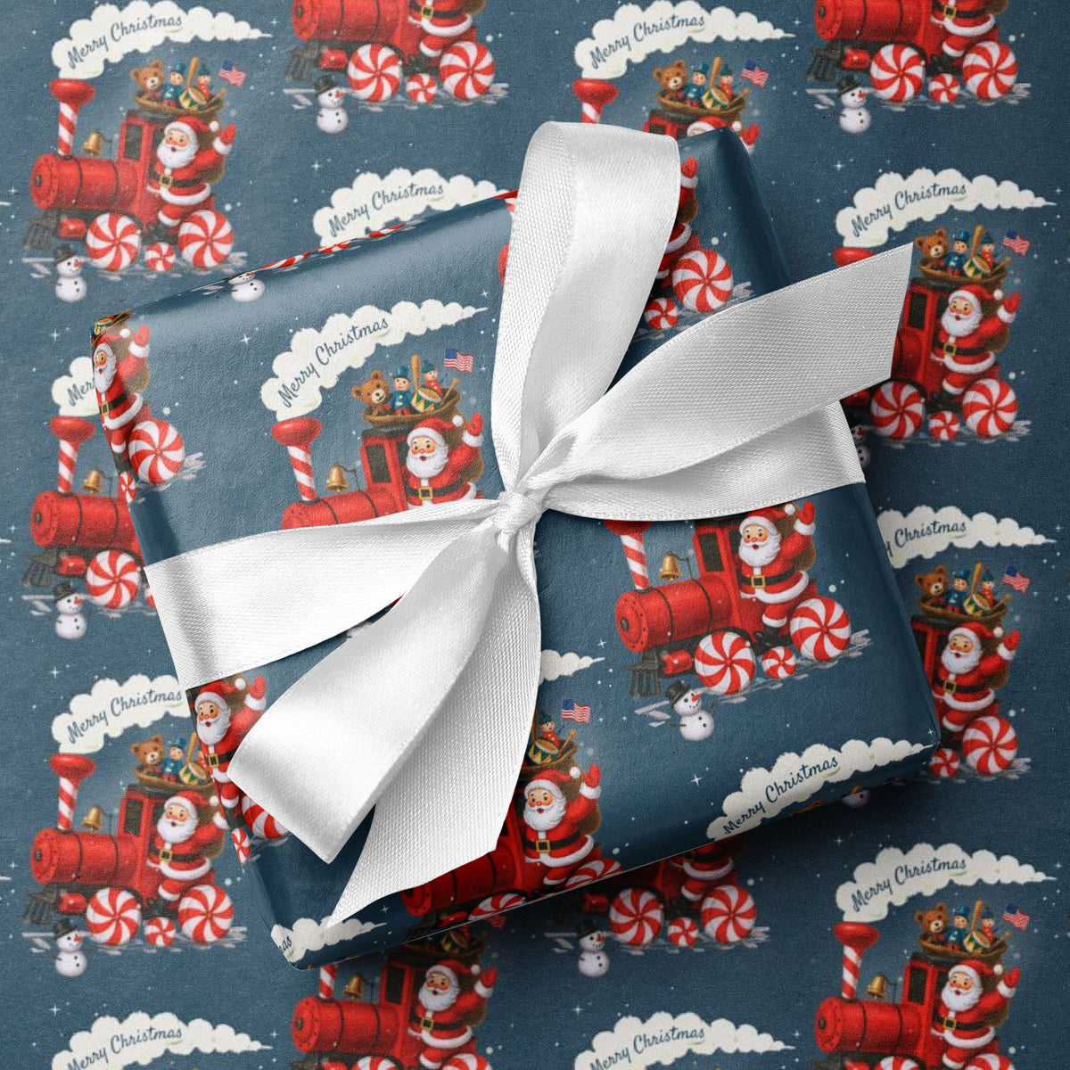 A gift box wrapped in blue Christmas-themed wrapping paper with a red Santa Claus train and candy cane pattern, tied with a white satin ribbon, placed on top of the same patterned paper.