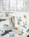Ivory wrapping paper with a repeating pattern of vintage blue and gold airplanes, shown wrapped around gift boxes on a table with scissors and ribbon nearby.