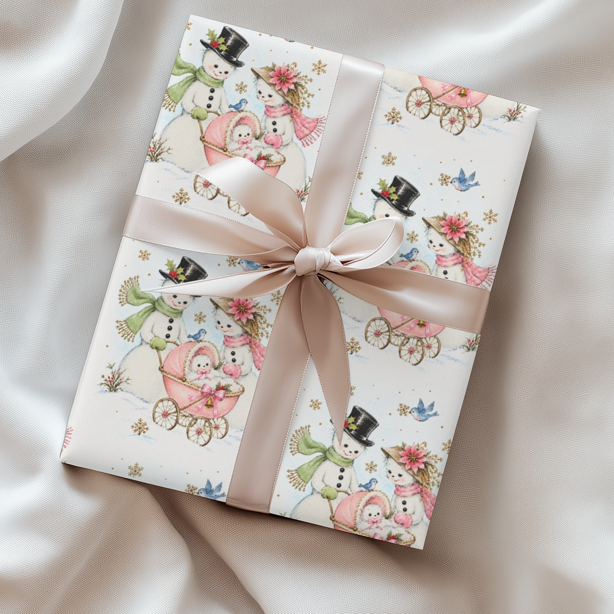 Gift wrapped in vintage-style Christmas wrapping paper with snowmen pushing a pink baby carriage and a blush satin ribbon, snowman baby girl gift wrap