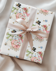 Gift wrapped in vintage-style Christmas wrapping paper with snowmen pushing a pink baby carriage and a blush satin ribbon, snowman baby girl gift wrap
