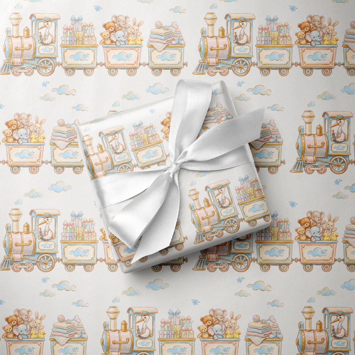 A gift box wrapped in matching baby-themed train patterned wrapping paper, tied with a white satin ribbon, placed on top of the same patterned wrapping paper.