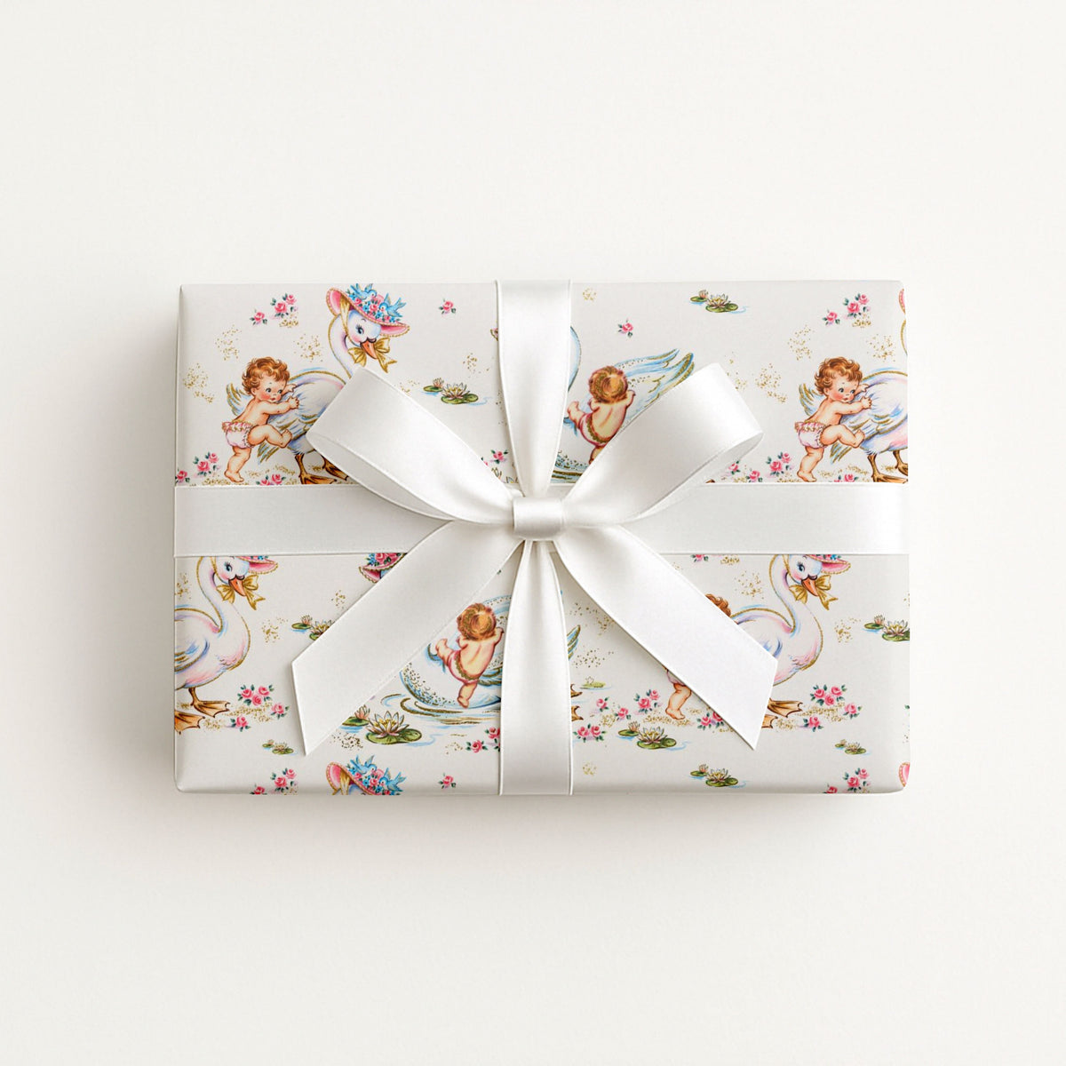 Gift wrapped in whimsical swan and baby wrapping paper with a white ribbon on a light background.