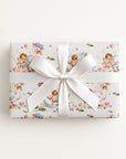 Gift wrapped in whimsical swan and baby wrapping paper with a white ribbon on a light background.