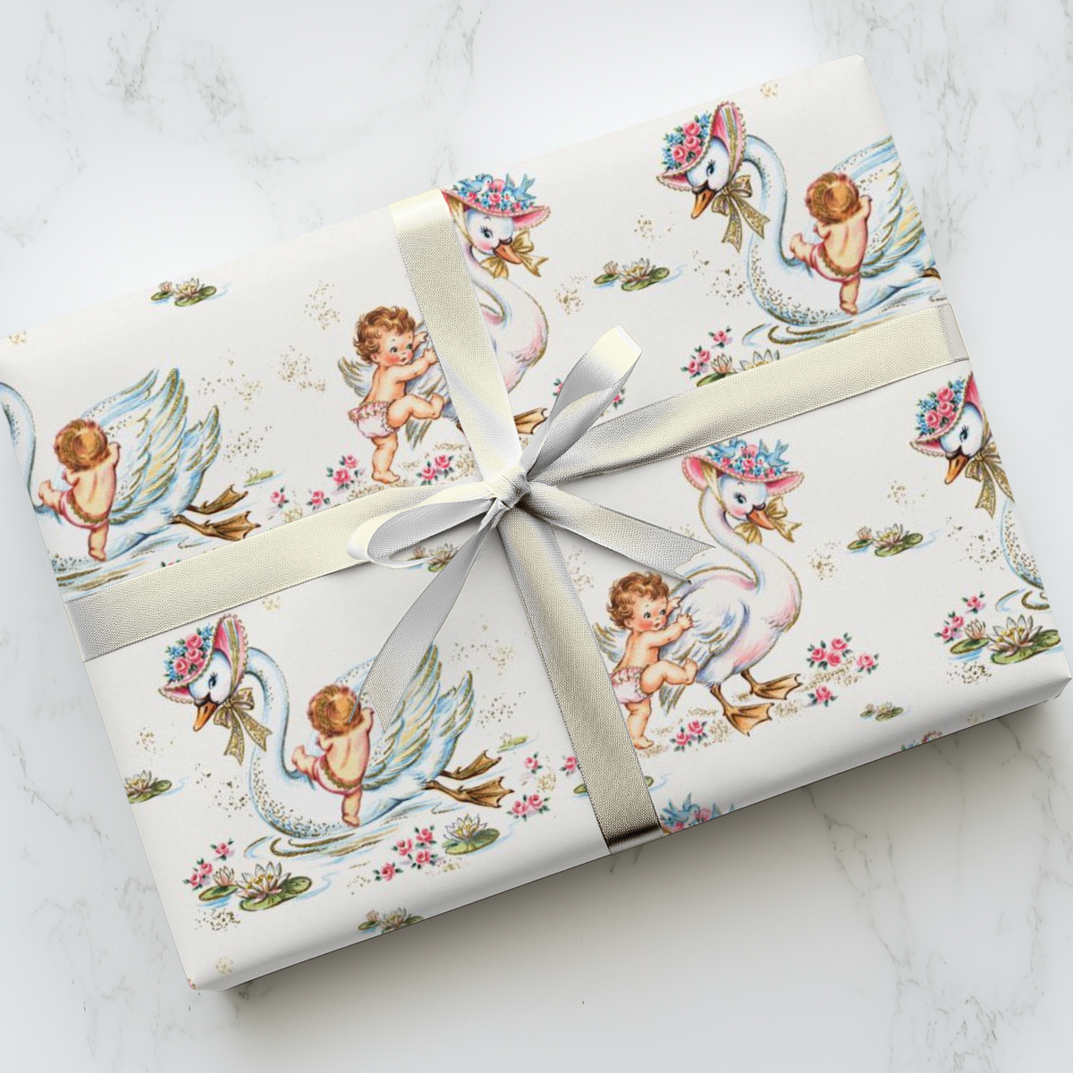 Gift wrapped in vintage-style baby and swan wrapping paper on a marble surface.