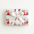 Gift wrapped in vintage-style triplets first Christmas wrapping paper with a woman in a red coat trimmed with white fur pushing a pram with three sleepy babies, tied with a white satin ribbon bow, Winter Wonderland triplets baby shower gift wrap