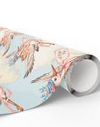 Roll of twin girls stork wrapping paper showing storks in blue clouds with pink ribbons