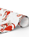 A roll of vintage-style twins first Christmas wrapping paper with a repeating pattern of a woman in a red coat trimmed with white fur pushing a pram with two sleepy babies, wreath-trimmed lampposts and snowy fir trees on a white background, Double the Joy twin baby shower gift wrap