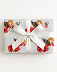 Flat lay of a gift wrapped in vintage-style patriotic angel Christmas wrapping paper with trumpet angels and a white satin bow