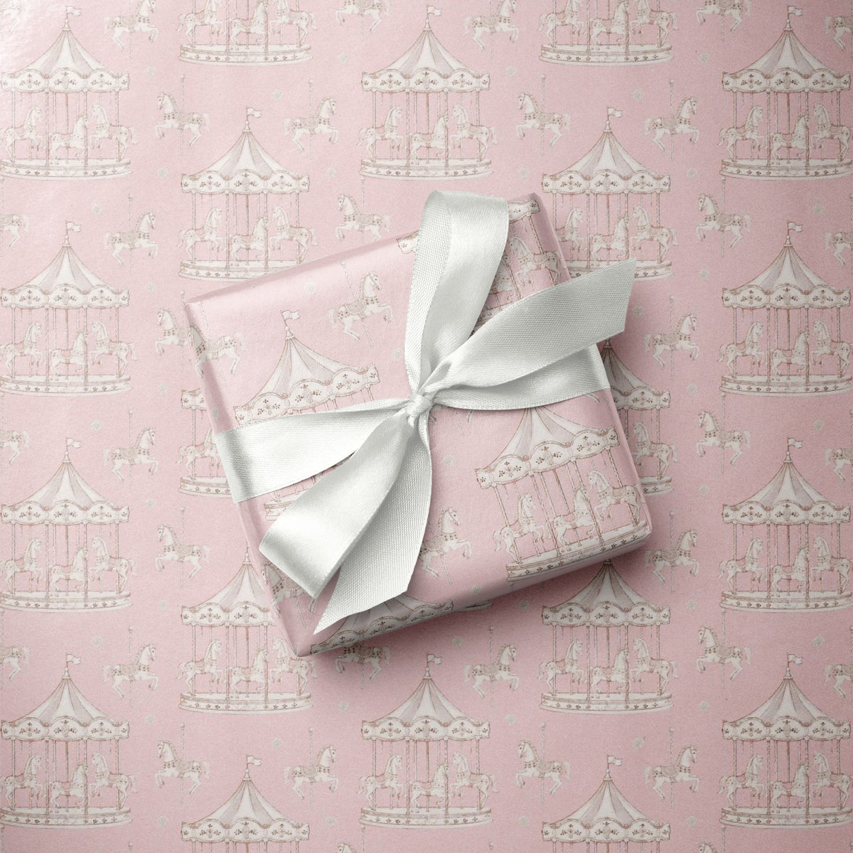 Close-up of vintage carousel gift wrap paper highlighting the fine white line-art pattern of carousel horses and whimsical merry-go-round poles.