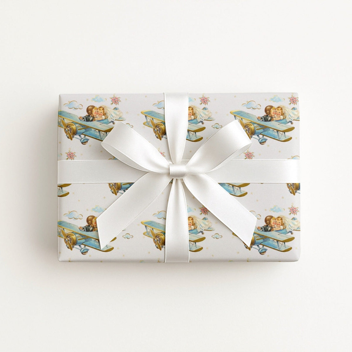 Wedding gift wrapped in vintage-style airplane wrapping paper with white satin bow.