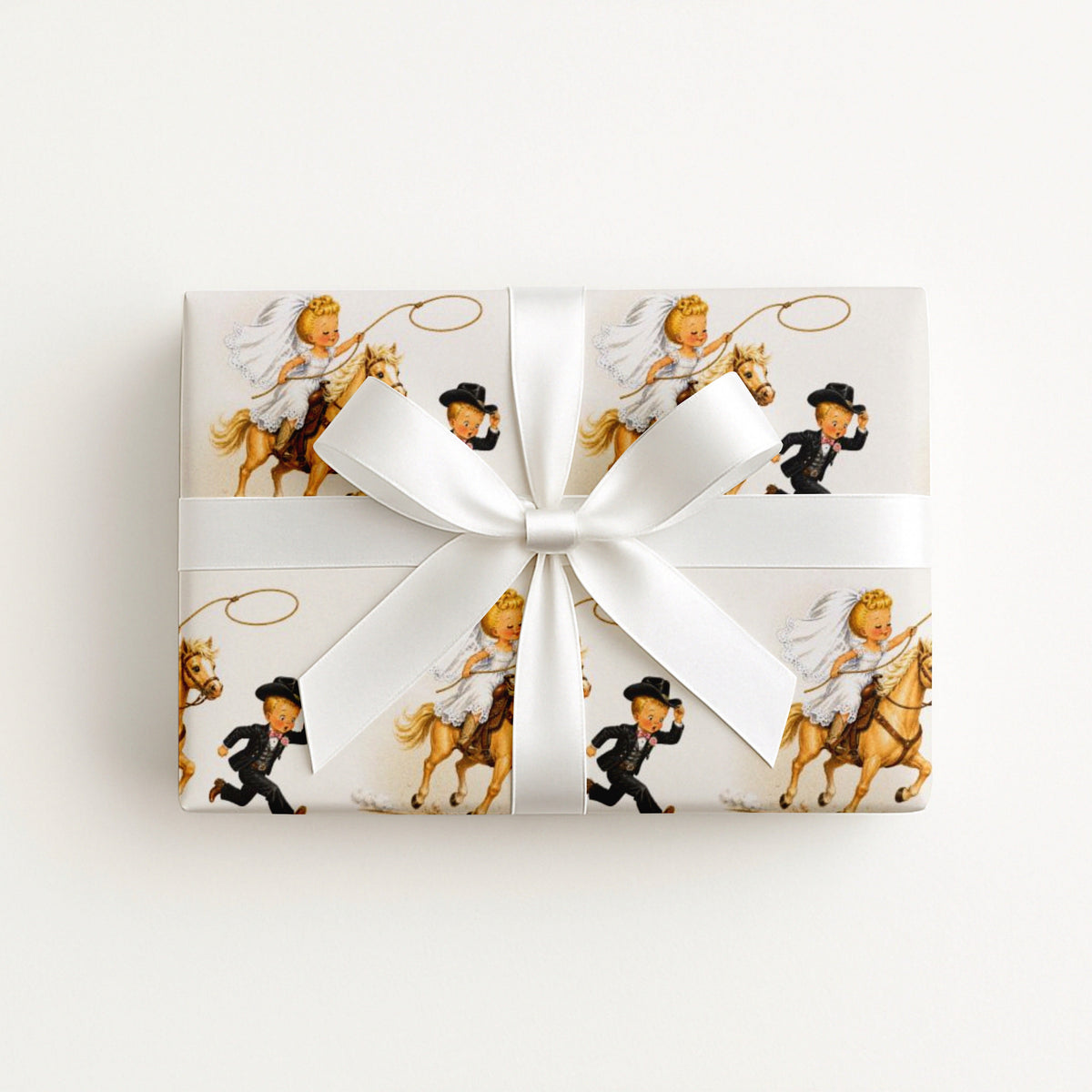 Vintage-style western wedding wrapping paper with a cowgirl bride on a palomino horse swinging a lasso while the groom in a cowboy hat runs ahead.