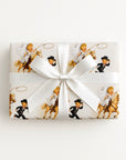 Vintage-style western wedding wrapping paper with a cowgirl bride on a palomino horse swinging a lasso while the groom in a cowboy hat runs ahead.