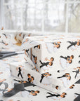 Vintage wedding wrapping paper with a repeating pattern of  of dancing bride and groom couples shown wrapped around gift boxes on a table with scissors and ribbon near a bright window.