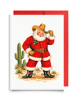 Vintage-style cowboy Santa tipping his hat in a red suit and spurred boots beside a desert cactus, western Santa Christmas card